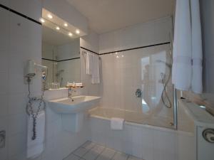 W łazience znajduje się wanna, umywalka i prysznic. w obiekcie Privathotel Bremer w mieście Bergisch Gladbach