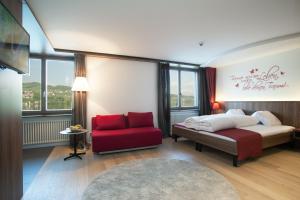 una camera da letto con un letto e una sedia rossa di Seehotel Delphin a Meisterschwanden