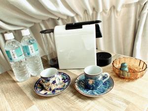 einen Tisch mit zwei Tassen, einem Toaster und Wasser in der Unterkunft Nekoana Glamping - Vacation STAY 39635v in Fujikawaguchiko