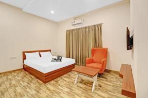 a bedroom with a bed and an orange chair at Sri Udupi park phoenix mall in Bangalore