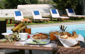 een tafel met een ontbijt van brood en zoete deegwaren naast een zwembad bij Villa Irini in Spetses