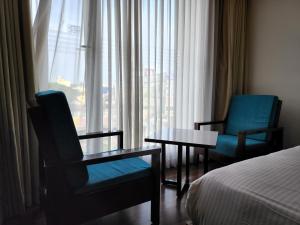 a hotel room with a bed and two chairs and a table at Hotel Preethi International in Mysore