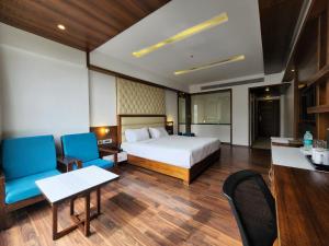 a hotel room with a bed and a desk and chairs at Hotel Preethi International in Mysore