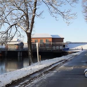 a building next to a river with snow on the ground at Bi uns im Norden in Brunsbüttel +23 photos
