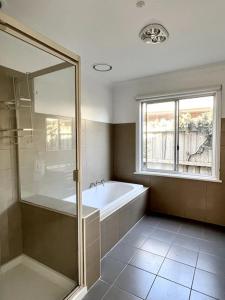 uma casa de banho com uma banheira e uma janela em Beach Rd Kids & Pet Friendly Free Parking em Mordialloc