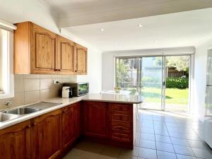 a kitchen with wooden cabinets and a large window at Beach Rd Kids & Pet Friendly Free Parking in Mordialloc