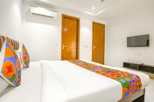 um quarto branco com uma cama grande e um cobertor colorido em FabExpress Aerosky Deluxe em Nova Deli
