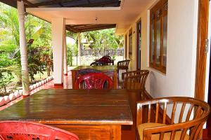 uma sala de jantar com uma mesa de madeira e cadeiras em Beach Walk Villa em Trincomalee