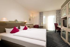 a hotel room with a large bed with red pillows at ACHAT Hotel Reilingen Walldorf in Reilingen