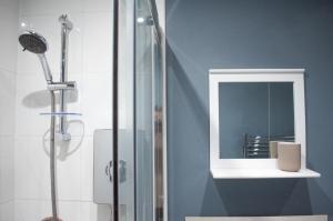 y baño con ducha y espejo. en Bedford Rd Apartment Ideal for Hospital & Town Centre en Kempston