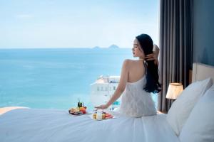 a woman sitting on a bed with a tray of food at Libra Nha Trang in Nha Trang