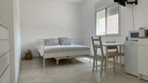 a white room with a table and a bed and a chair at אירוח ליד אילת compliment near Eilat in Beʼer Ora