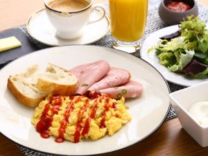 a plate with eggs sausage and bread and a cup of coffee at APA Hotel Roppongi Ekimae in Tokyo