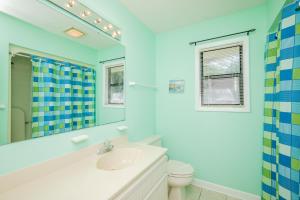 a bathroom with a sink and a toilet and a mirror at 9th Tee in Caswell Beach +67 photos