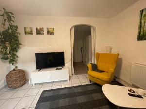 salon z telewizorem i żółtym krzesłem w obiekcie Appartement in Bad Waldsee w mieście Bad Waldsee