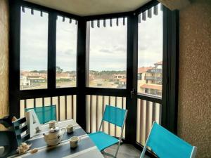 a room with a table and chairs and windows at V-Landes 01 T2 dans résidence avec piscine face au lac marin in Vieux-Boucau-les-Bains