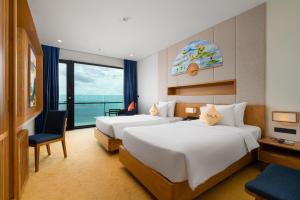 two beds in a hotel room with a view of the ocean at Sala Danang Beach Hotel in Danang