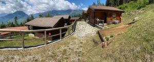 a small house on a hill next to a fence at Camping & Chalet Pian della Regina in Cevo