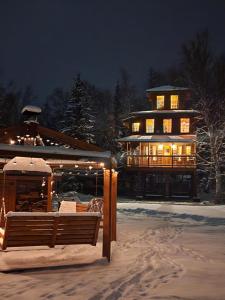 una grande casa con luci accese nella neve di The Eagle's Nest Treehouse Cabin a Palmer