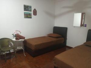 a room with two beds and a table with a chair at Amaryllis guest house PD in Port Dickson