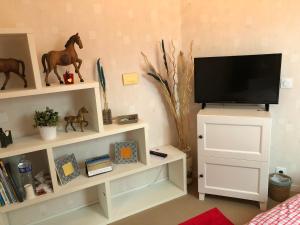 sala de estar con TV en un estante blanco en Coquelicot, en Hermanville-sur-Mer