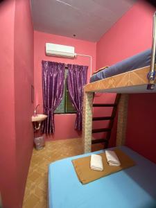 een slaapkamer met roze muren en een stapelbed bij Rumah Hentian Ayah in Kampung Kuala Besut