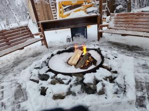 eine Feuerstelle im Schnee neben einer Bank in der Unterkunft The Eagle's Nest Treehouse Cabin in Palmer