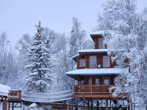 ein großes Holzhaus mit Schnee darauf in der Unterkunft The Eagle's Nest Treehouse Cabin in Palmer