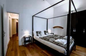 1 dormitorio con 1 cama negra con dosel y 2 mesas en Borgo San Jacopo Deluxe by 360Rentals, en Florencia