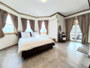 a bedroom with a large bed and large windows at Another world pension in Gyeongju