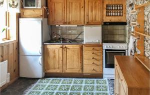 cocina con armarios de madera y nevera blanca en Awesome Home In Srsjn With Kitchen, en Sörsjön