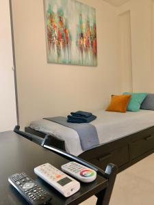 a bed with two remote controls on a table at Small Private Studio in heart of Valencia - Rusafa in Valencia