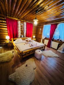 a bedroom with a large bed in a wooden cabin at Cabana Dzsesszika&Erik in Kàszonuifalù