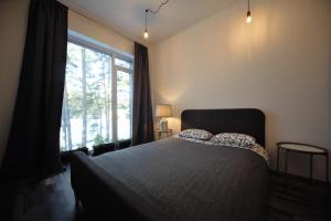 ein Schlafzimmer mit einem Bett und einem großen Fenster in der Unterkunft Loft 3 rooms riverside by Gauja.Club - Residences in Gauja