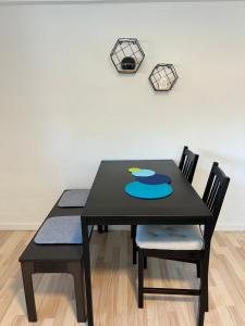 una mesa negra con dos sillas y un reloj en la pared en Hyggelig & lys kælderlejlighed, en Herning