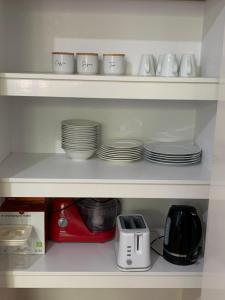 un estante con tazas, platos y tostadora en Sandalwood Guest Room en Margaret River