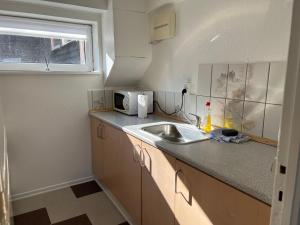 a small kitchen with a sink and a microwave at Hyggelig & lys kælderlejlighed in Herning