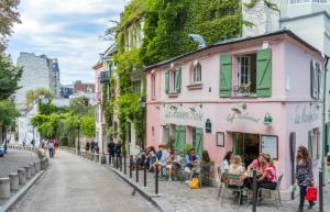 a group of people sitting at tables outside a pink building at Rare! private garden in Paris, close to Sacre Coeur Basilica! in Paris