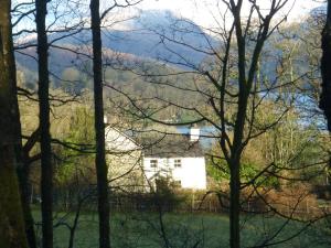 a white house in a field with mountains in the background at Slack Cottage in Ambleside