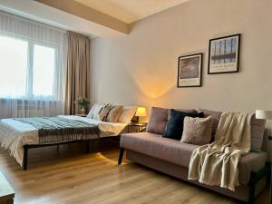 a living room with a couch and a bed at Студия МЕРЕНГА в центре Алматы in Almaty