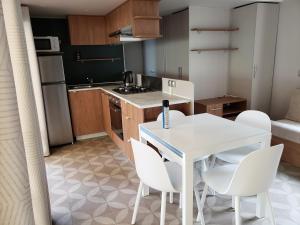 a small kitchen with a white table and white chairs at CAMPING SIBLU LA CARRABASSE MOBIL HOME OL21 in Vias