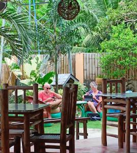 Ein Mann und eine Frau sitzen an Tischen im Garten in der Unterkunft Greenhut Pension & Bar in Jagna