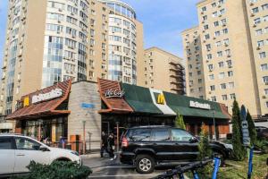a black suv parked in front of a building with tall buildings at Студия МЕРЕНГА в центре Алматы in Almaty