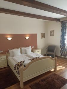 a bedroom with a large bed and a chair at Gasthof Clara in Sibiu