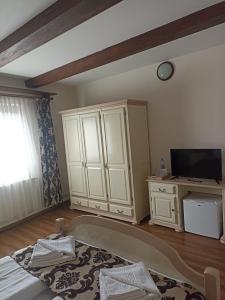 a bedroom with a bed and a tv and a cabinet at Gasthof Clara in Sibiu