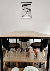 a wooden table with chairs and cups and glasses at Cosy Dunkerquois in Dunkerque