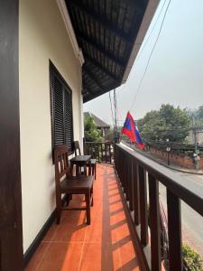 a balcony of a house with two chairs and a flag at Villa Champa in Luang Prabang
