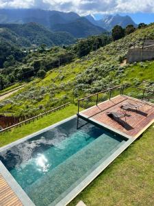 una piscina con terraza y montañas de fondo en MORADA DOS IPÊS, en Teresópolis