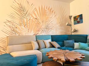 eine blaue Couch in einem Wohnzimmer mit einem Palmenmilch in der Unterkunft Natur & Jasmin Chambres d'hôtes naturistes en Provence in Lorgues