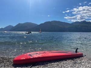 a red surfboard on the shore of a body of water at Ferienwohnung Malcesine ,Val di Sogno - Gardasee Italien in Malcesine